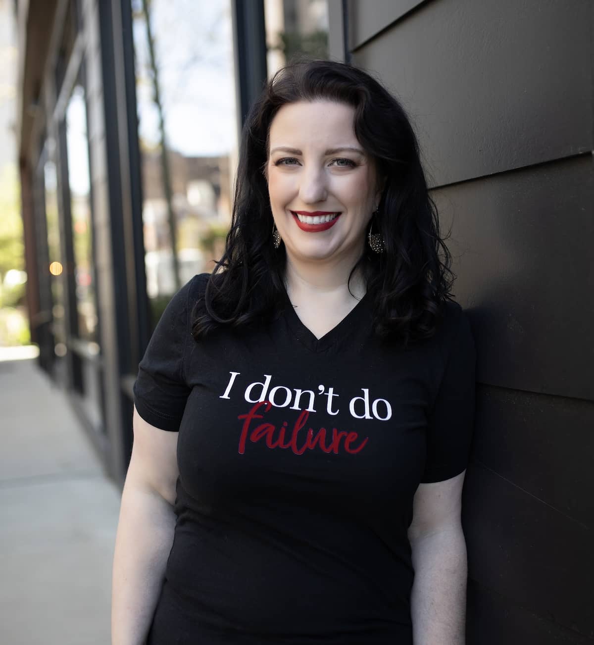 Monica, a white woman with dark hair, wearing a black v-neck swearshirt that says "I don't do failure"